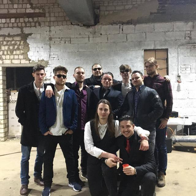 Die Goodfellas: die Crew in dunklen Jacken und Sonnenbrillen vor einer weißen Backsteinwand